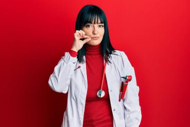 Doktor üniforması giyen genç İspanyol kadın ve steteskop ağzı ve dudakları parmaklarıyla fermuar gibi kapalı. gizli ve sessiz, tabu konuşması 