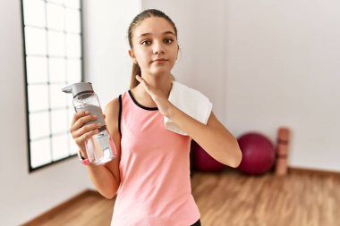 Genç esmer kız spor giysisi giyiyor su şişesi tutuyor boğazını bıçak niyetine kesiyor, saldırganlığı şiddetle tehdit ediyor. 