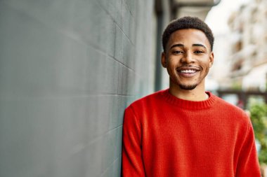 Yakışıklı Afro-Amerikan adam gri duvarın üzerinde duruyor.