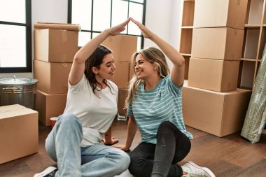 Genç çift yeni evlerinde kollarını kaldırarak ev sembolü yapıyor..