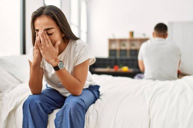 Genç Latin bir çiftin başı dertte. Ellerin başının üstünde, yatakta oturuyorsun..