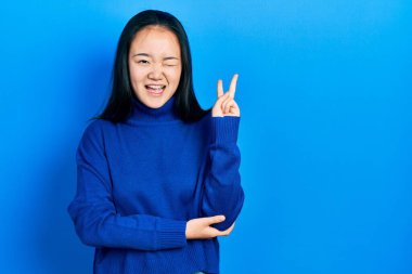 Sıradan kıyafetler giyen genç Çinli kız kameraya gülümseyen ve zafer işareti yapan. İki numara.. 