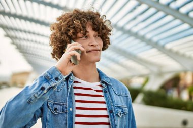 Genç İspanyol adam şehirde telefonla konuşuyor.