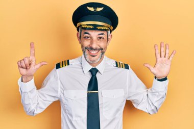 Yakışıklı, orta yaşlı, gri saçlı, uçak pilotu üniforması giyen, 7 numaralı parmaklarıyla gösteriş yapan, kendine güvenen ve mutlu bir adam.. 