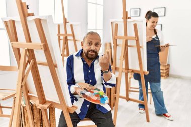 Sanat stüdyosundaki kıdemli sanatçı seni çağırıyor. El kol hareketi yap. Mutlu bir şekilde karşıla ve gülümse. 