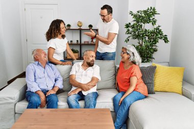 Orta yaşlı arkadaşlar evdeki kanepede mutlu mesut oturuyorlar..