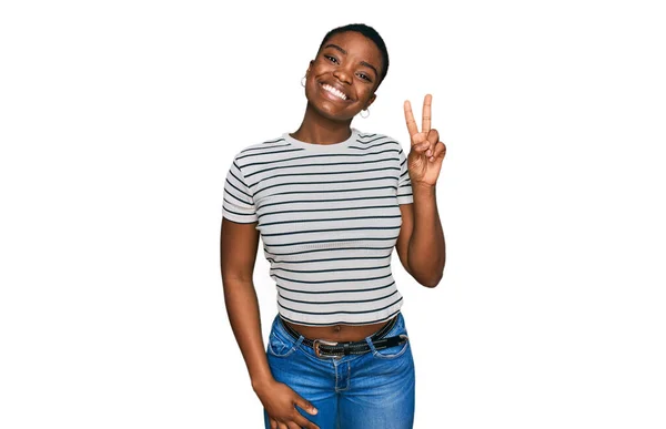 カジュアルな服を着た若いアフリカ系アメリカ人女性が 勝利のサインをしてカメラに顔をウィンクして微笑んでいる — ストック写真