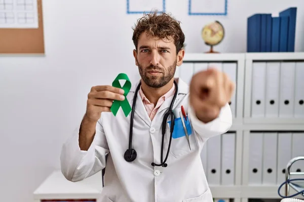 Young Hispanic Doctor Man Holding Support Green Ribbon Clinic Pointing — Stock Photo, Image