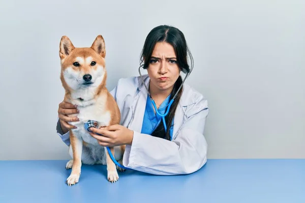 Красивая Латиноамериканская Ветеринар Женщина Проверяет Здоровье Собаки Скептически Нервно Хмурясь — стоковое фото