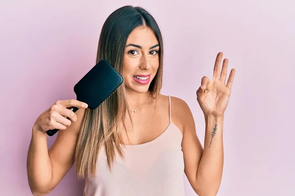 指でOkサインを行う櫛を使用して若いヒスパニック系の女性のスタイリングの髪 笑顔優しいジェスチャー優れたシンボル — ストック写真