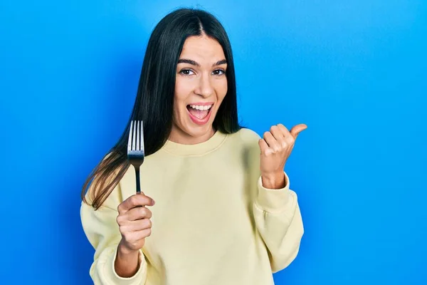 Young Brunette Woman Holding One Silver Fork Pointing Thumb Side — Stock Photo, Image