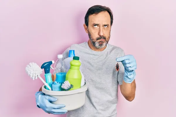 中年惊慌失措的男人拿着清洁用品 手里拿着蟑螂 用嘴和眼睛做鱼脸 疯狂而滑稽 — 图库照片