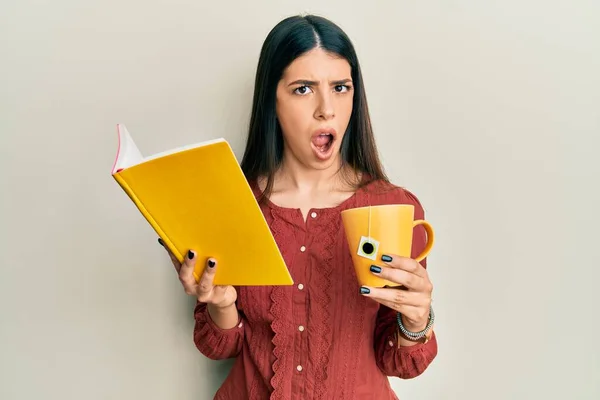 Young Hispanic Woman Reading Book Drinking Cup Tea Shock Face — Stock Photo, Image