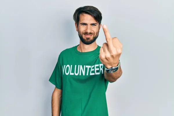 Young Hispanic Man Wearing Volunteer Shirt Showing Middle Finger Impolite — Stockfoto