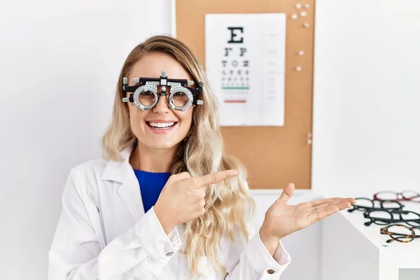 Joven Mujer Óptica Hermosa Con Gafas Optometría Clínica Sorprendida Sonriendo —  Fotos de Stock