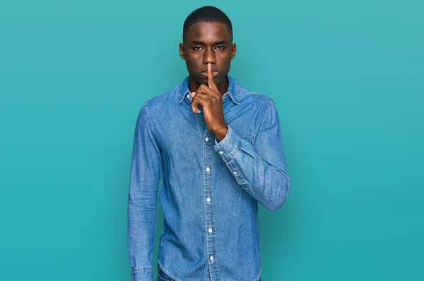 若いアフリカ系アメリカ人の男性は 唇に指で静かになるように頼むカジュアルな服を着ていた 沈黙と秘密の概念 — ストック写真