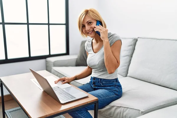 Middelbare Leeftijd Blonde Vrouw Praten Smartphone Met Behulp Van Laptop — Stockfoto