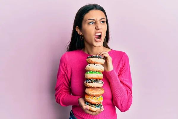 Young Hispanic Woman Holding Pile Tasty Colorful Doughnuts Angry Mad — Fotografia de Stock