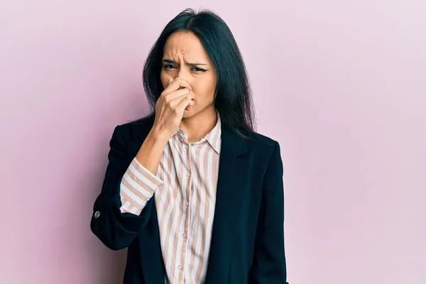 若いヒスパニック系の女の子は 鼻の上に指で息を保持し ビジネス服を着て何か臭いと嫌な 耐え難い匂いを嗅ぐ 臭いが悪い — ストック写真