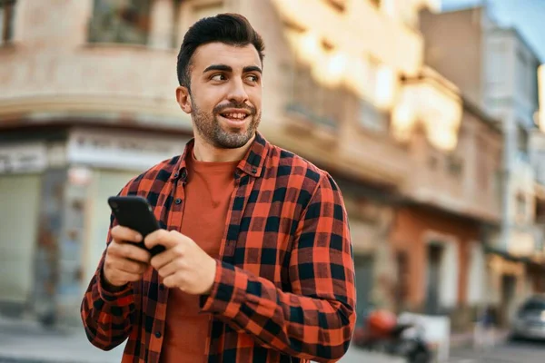 Joven Hombre Hispano Sonriendo Feliz Usando Smartphone Ciudad —  Fotos de Stock