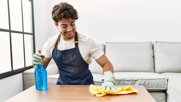 Νεαρός Ισπανός Άντρας Χαμογελάει Αυτοπεποίθηση Καθαρίζοντας Τραπέζι Στο Σπίτι — Φωτογραφία Αρχείου