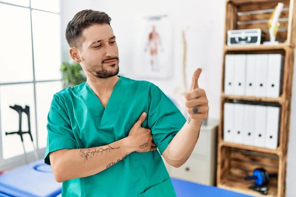 Young Physiotherapist Man Working Pain Recovery Clinic Looking Proud Smiling — Φωτογραφία Αρχείου