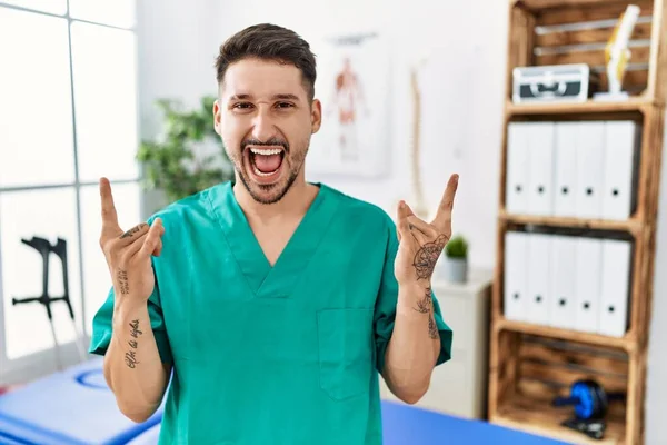Young Physiotherapist Man Working Pain Recovery Clinic Shouting Crazy Expression — Stockfoto