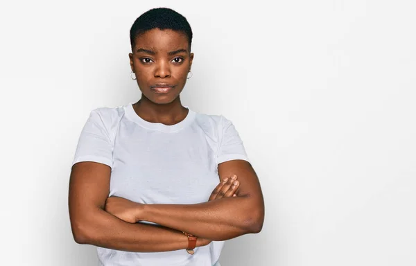 カジュアルな白いTシャツを着た若いアフリカ系アメリカ人女性は懐疑的で緊張しており 両腕を組んで顔をしかめた表情を否定している 否定的な人 — ストック写真