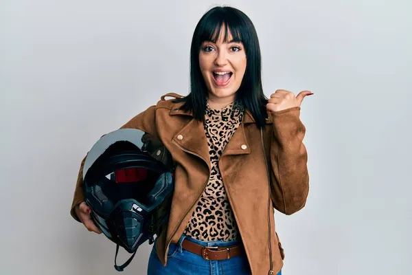 Young Hispanic Woman Holding Motorcycle Helmet Pointing Thumb Side Smiling — Stock Photo, Image