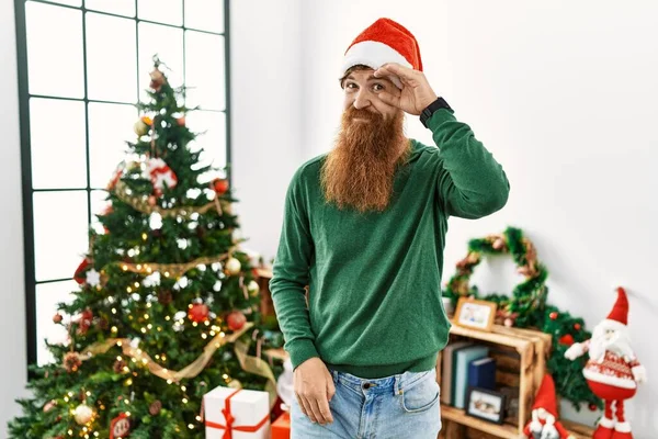 Roodharige Man Met Lange Baard Draagt Kerstmuts Door Kerstboom Bezorgd — Stockfoto