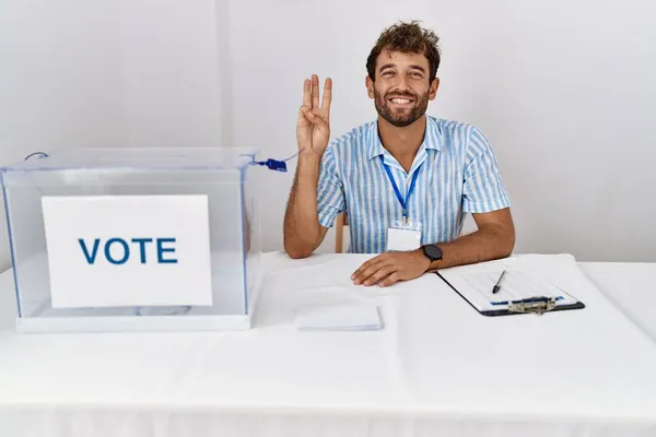 年轻英俊的男子在政治选举中 坐在选票旁 用第三指尖 面带微笑 自信而快乐 — 图库照片