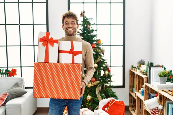 Jovem Hispânico Sorrindo Confiante Segurando Presentes Natal Casa — Fotografia de Stock