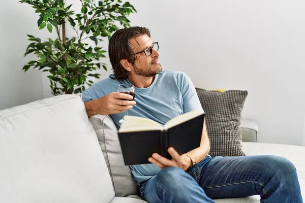 Biały Mężczyzna Średnim Wieku Czyta Książki Pijąc Wino Domu — Zdjęcie stockowe