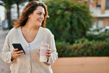 Genç İrlandalı artı uzun boylu kız akıllı telefon kullanıp şehirde kahve içiyor..