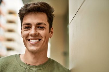 Genç İspanyol adam gülümseyerek şehirde mutlu mesut dikiliyor..