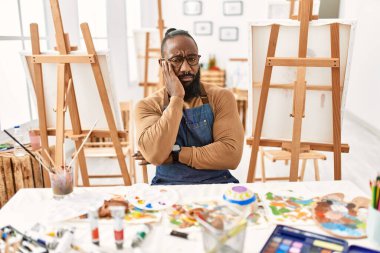 African american artist man at art studio thinking looking tired and bored with depression problems with crossed arms. 