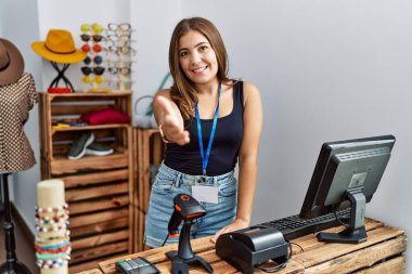 Perakende dükkanında açık mesajla pankart tutan esmer genç bir kadın selamlama ve hoş geldin demek için gülümseyerek tokalaşıyor. başarılı iş. 