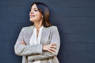 Genç İspanyol iş kadını şehirde çapraz hareketlerle mutlu gülümsüyor..