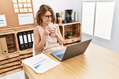 Orta yaşlı İspanyol kadın ofiste kahve içiyor.