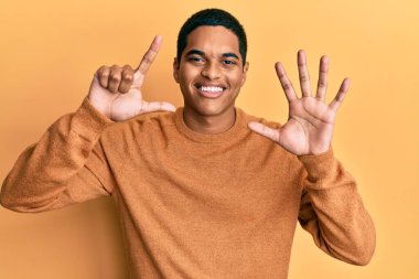 Genç, yakışıklı, sıradan bir süveter giyen, yedi numaralı parmaklarını gösterip, gülümseyen, kendinden emin ve mutlu bir İspanyol.. 