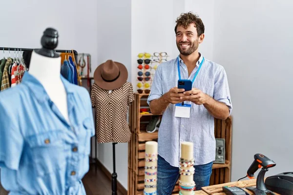 衣料品店で働くスマートフォンを使っている若いヒスパニック系の店主 — ストック写真