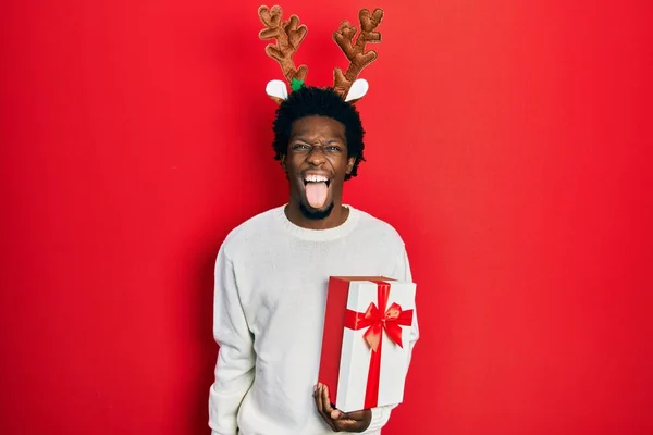 Молодой Африканский Американец Рождественской Шляпе Подарком Торчащим Языком Довольный Смешным — стоковое фото