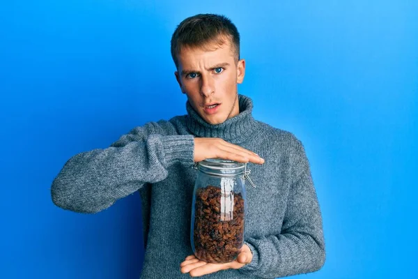 Young Caucasian Man Holding Jar Raisins Shock Face Looking Skeptical — Fotografia de Stock