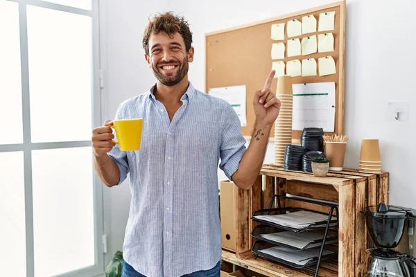 Jovem Homem Bonito Beber Café Xícara Escritório Sorrindo Feliz Apontando — Fotografia de Stock