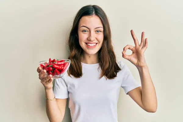 Jovem Morena Segurando Pimentas Vermelhas Fazendo Sinal Com Dedos Sorrindo — Fotografia de Stock