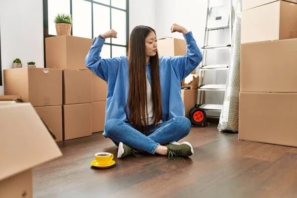 Young Chinese Girl Sitting Floor New Home Showing Arms Muscles — Stockfoto