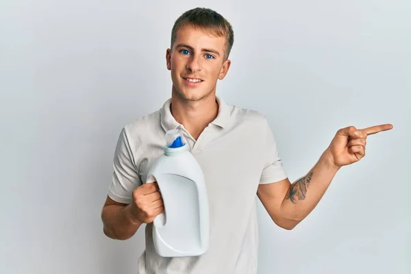 Young Caucasian Man Holding Detergent Bottle Smiling Happy Pointing Hand — Photo