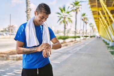 Genç İspanyol adam dışarıda akıllı saat kullanıyor.