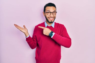 Sakallı, iş gömleği ve gözlüklü İspanyol adam kameraya hayret ediyor ve gülümsüyor.. 