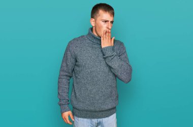 Gündelik kıyafetler giyen genç sarışın adam ağzıyla ağzını kapatmaktan sıkılmış. Huzursuz ve uykulu.. 